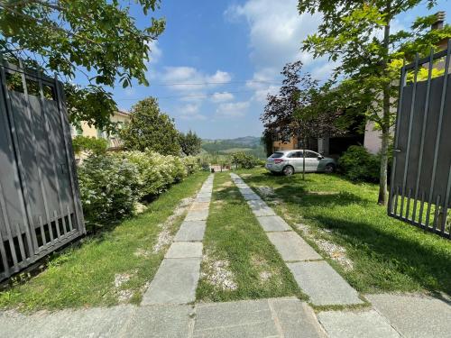 a path through a garden with a car in the distance at Cascina Vicentini in Alfiano Natta