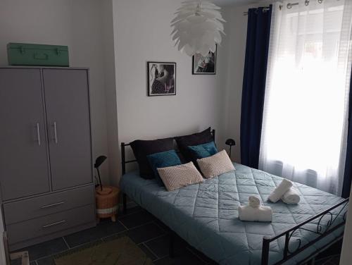 1 dormitorio con 1 cama con sábanas y almohadas azules en Le Cocooning, en Vierzon