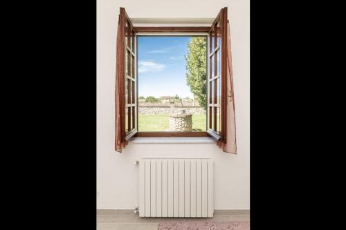 an open window with a radiator and a view of a field at Oasi di Pace Sarzana in Luni