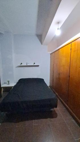 a bedroom with a bed and a wooden cabinet at Delfina -Catamarca, Zona Centro in San Fernando del Valle de Catamarca