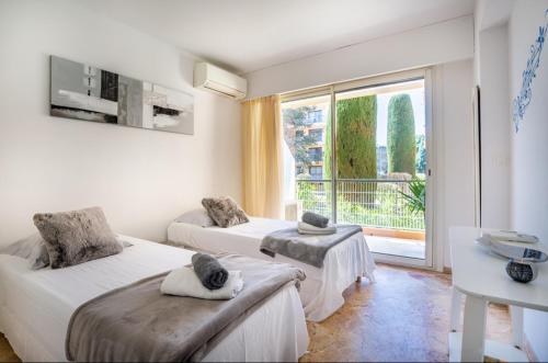 Cette chambre comprend deux lits et une grande fenêtre. dans l'établissement Belle résidence arborée, Appart climatisé, piscine, à 500m de la mer, à Sainte-Maxime
