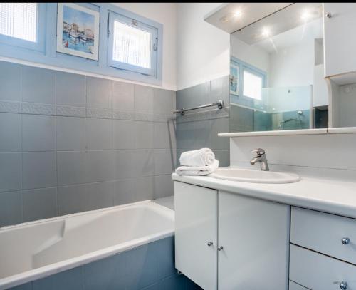 une salle de bain blanche avec un lavabo et une baignoire dans l'établissement Belle résidence arborée, Appart climatisé, piscine, à 500m de la mer, à Sainte-Maxime