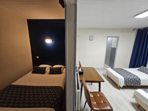 a room with two beds and a desk and a table at Escal Hôtel in Étaples
