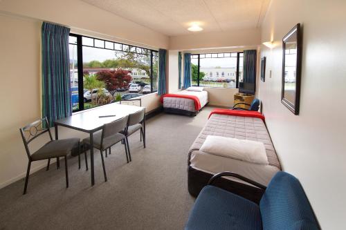 ein Krankenhauszimmer mit einem Bett, einem Tisch und Stühlen in der Unterkunft Ambassador Thermal Motel in Rotorua