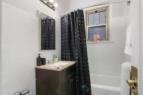 a bathroom with a black shower curtain and a sink at Modern Minimalist Studio Haven - Bstone 105 and 108 rep in Chicago