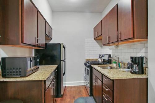 a kitchen with wooden cabinets and a black refrigerator at Modern and Minimalist Studio Apartment - Bstone 105 and 108 rep in Chicago