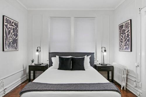 a white bedroom with a large bed with two night stands at Modern and Minimalist Studio Apartment - Bstone 105 and 108 rep in Chicago