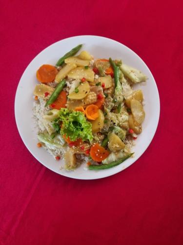 einen Teller mit Reis und Gemüse auf einem roten Tisch in der Unterkunft NEW LAYA NEEM RESORT AND RESTAURANT in Dambulla