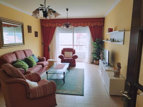 ein Wohnzimmer mit einem Sofa, 2 Stühlen und einem TV in der Unterkunft Banda del Rio in Bueu