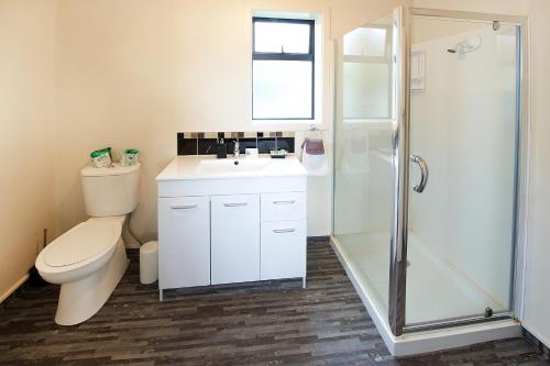 ein Bad mit einem WC, einem Waschbecken und einer Dusche in der Unterkunft Ambassador Thermal Motel in Rotorua