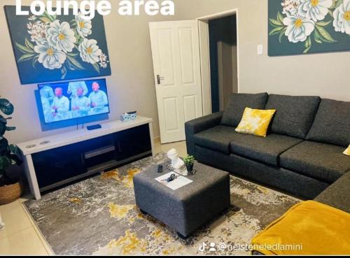 a living room with a couch and a tv at GoldenWays Apartment 3 in Mbabane