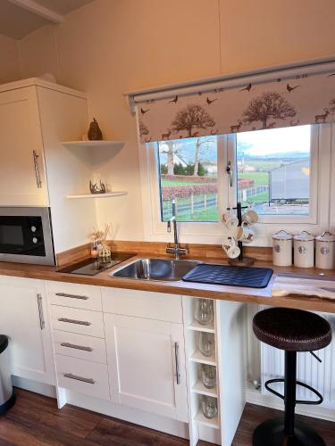 a kitchen with a sink and a window at Capledrae Farmstay Shepherds Huts in Cardenden