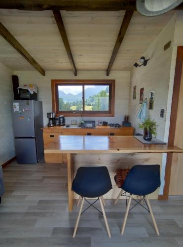 uma cozinha com uma grande mesa de madeira e 2 cadeiras em tiny house comuy em Ranco