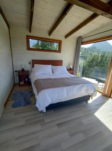 a bedroom with a bed and a large window at tiny house comuy in Ranco