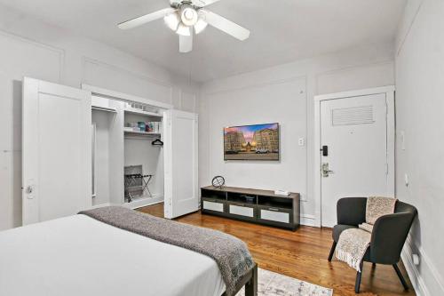 um quarto com uma cama, uma ventoinha de tecto e uma cadeira em Chic & Contemporary Studio Apartment - Bstone 120 em Chicago