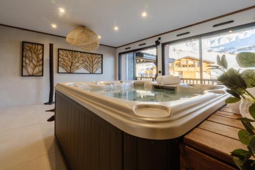 uma grande casa de banho com uma banheira e uma grande janela em Chalet Le Bouquetin em Saint-François-Longchamp