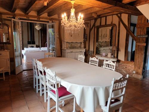 une salle à manger avec une grande table blanche et des chaises dans l'établissement Au bout du monde 2 piscine et spa, à Les Hermites