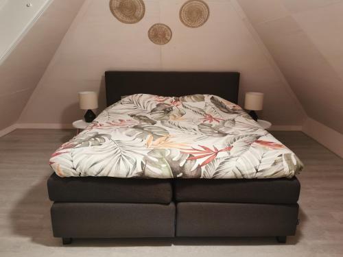 un letto in una camera con un telaio con un piumone di Ermerhoek, in de Hof a Erm