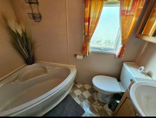 a bathroom with a tub and a toilet and a window at Morning side in Skegness