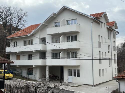 a white apartment building with a yellow car in front at Smeštaj Milutinn in Soko Banja