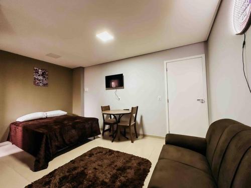 a bedroom with a bed and a table with a couch at Apartamento ótima localização in Passo Fundo