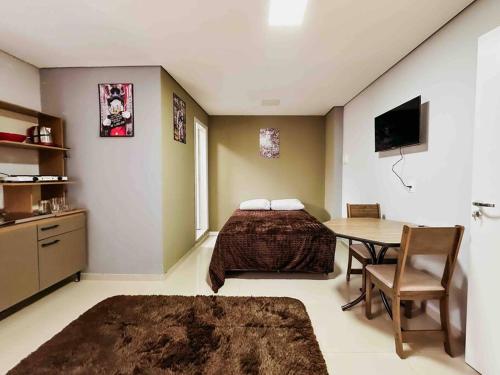 Un dormitorio con una cama y una mesa. en Apartamento ótima localização, en Passo Fundo
