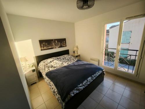 une chambre avec un lit et une grande fenêtre dans l'établissement Appartement T2 entre Roche et Mer, à Roquebrune-sur Argens