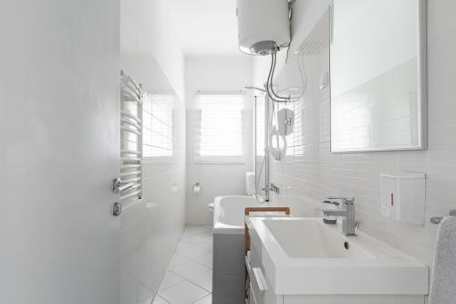 a white bathroom with a sink and a tub at Apartment Resorts Place in Split