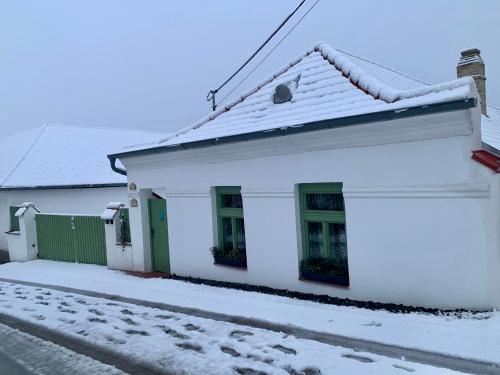 a white house with snow on the roof at Pannonhalma Várlak Vendégház in Pannonhalma