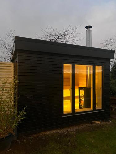 a black tiny house with a large window at Amazing Cottage & detached Annex sleeps 8, Extra Deep Hot tub, Super Fast wifi, New for 2024 is the addition of Wood Fired Sauna in Castle Douglas