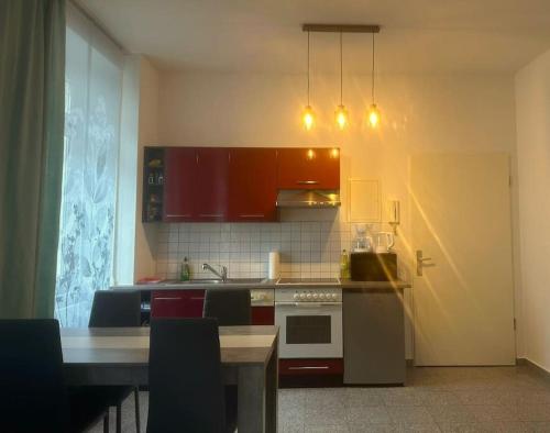 una cocina con armarios rojos y una mesa con mesa en Stilvolles Zuhause en Magdeburgo
