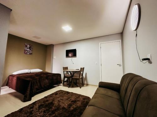 a living room with a couch and a bed and a table at Apartamento ótima localização in Passo Fundo