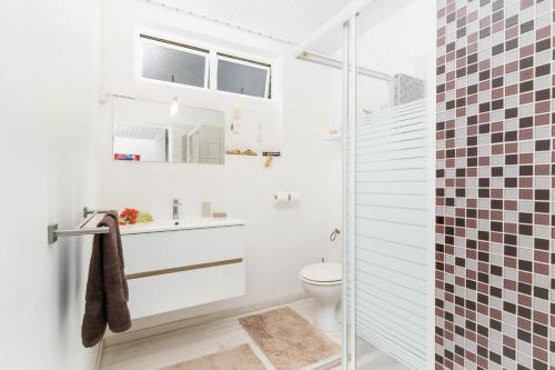 a white bathroom with a toilet and a shower at Villa Lodge - Bas de Villa avec piscine et vue océan et Moorea in Punaauia