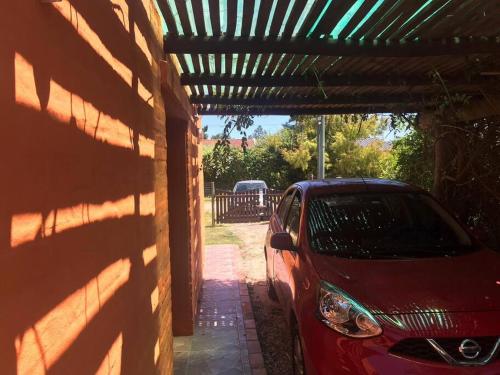 a red car parked under a wooden pergola at Roca de Guía. Casa con piscina y barbacoa cerca del mar in Punta del Este