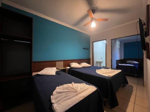 two beds in a room with a ceiling fan at Hotel Cesar Nogueira in Aparecida