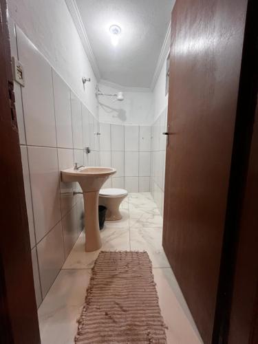 a white bathroom with a sink and a toilet at Hotel Cesar Nogueira in Aparecida