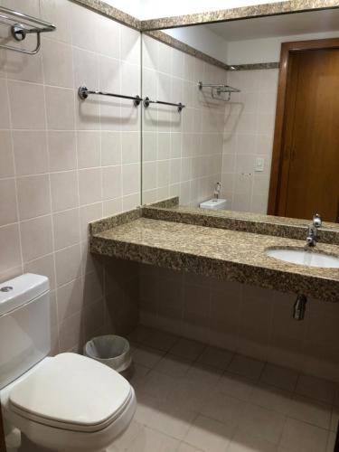a bathroom with a toilet and a sink and a mirror at Flat 609 - Comfort Hotel Taguatinga in Brasilia