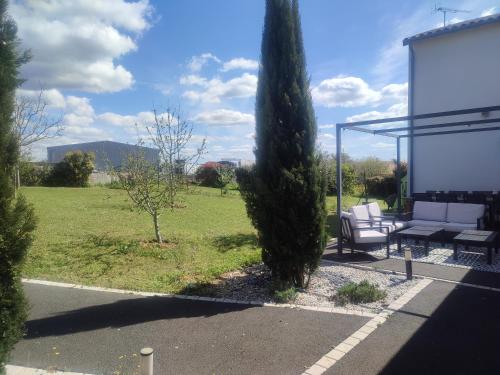 a patio with two white chairs and a tree at Charmante maison près du Futuroscope in Saint-Georges-lès-Baillargeaux