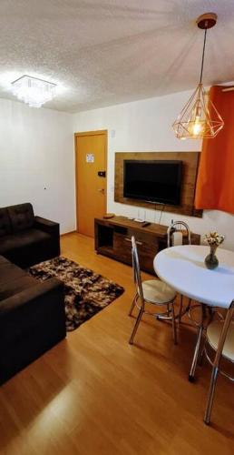 a living room with a couch and a table and a tv at Apartamento completo, privativo, ótima localização (Próximo ao Aeroporto) in Campo Grande