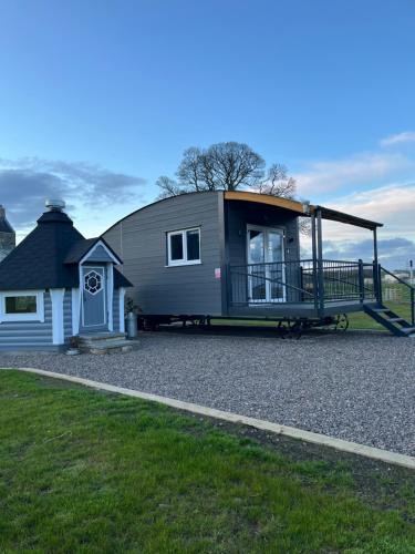 a tiny house on a trailer parked next to a house at Capledrae Farmstay Shepherds Huts in Cardenden