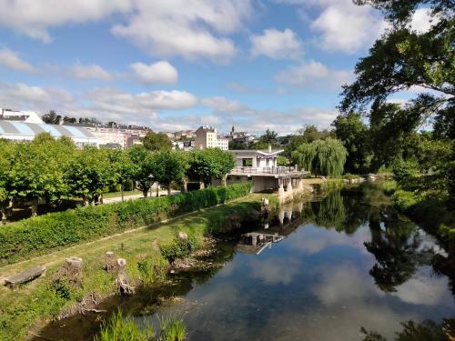 a view of a river with buildings in the background at Albergue HR in Sarria