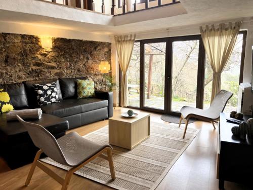 una sala de estar con un sofá de cuero negro y sillas en Retiro de Gondramaz - Whole house, Casa inteira 200 m2, en Gondramaz