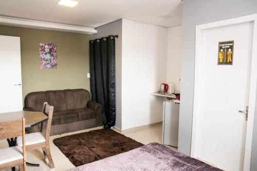 ein Wohnzimmer mit einem Sofa und einem Tisch in der Unterkunft Studio próximo Aeroporto e UPF in Passo Fundo