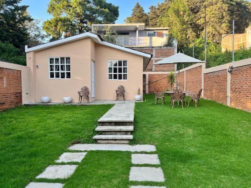 een tuin met een bakstenen muur en een huis bij La Casita in Pátzcuaro