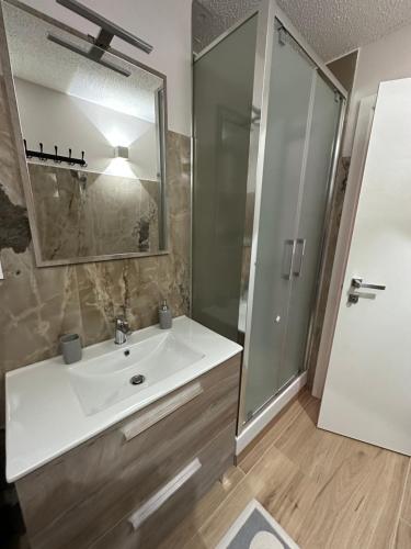 ein Badezimmer mit einem weißen Waschbecken und einer Dusche in der Unterkunft BELLAVISTA APARTMENT in Passo del Tonale