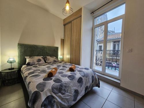 une chambre avec un lit et une grande fenêtre dans l'établissement le contemporain-2 chambres-vue Eglise saint paul, à Nîmes