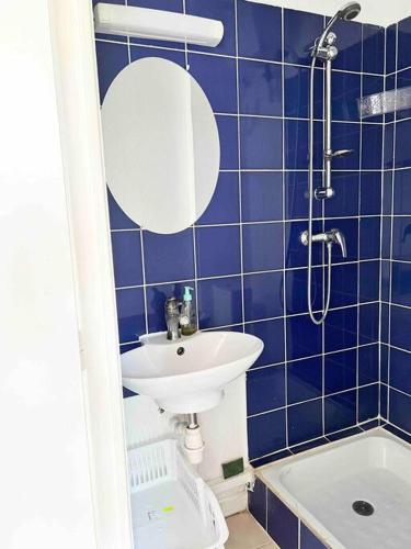 a blue tiled bathroom with a sink and a mirror at Studio Cosi Sxm in Marigot