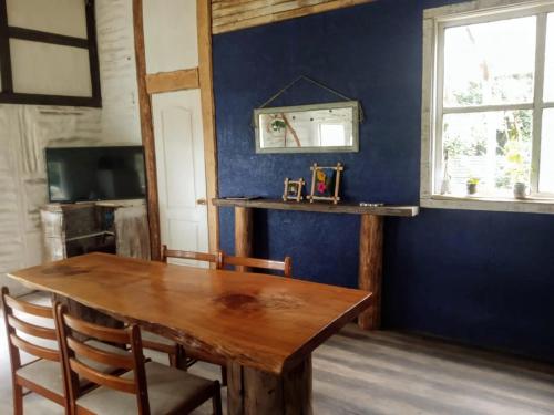 a dining room with a wooden table and a blue wall at Cabaña en el bosque de Chiloé in Quemchi