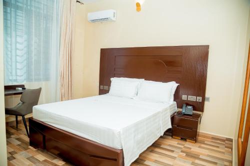 ダル・エス・サラームにあるANINY HOTELのベッドルーム1室(大型ベッド1台、木製ヘッドボード付)
