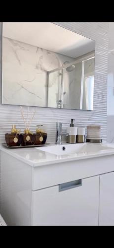 ein weißes Badezimmer mit einem Waschbecken und einem Spiegel in der Unterkunft Home Silva Sanches in Quinta do Conde